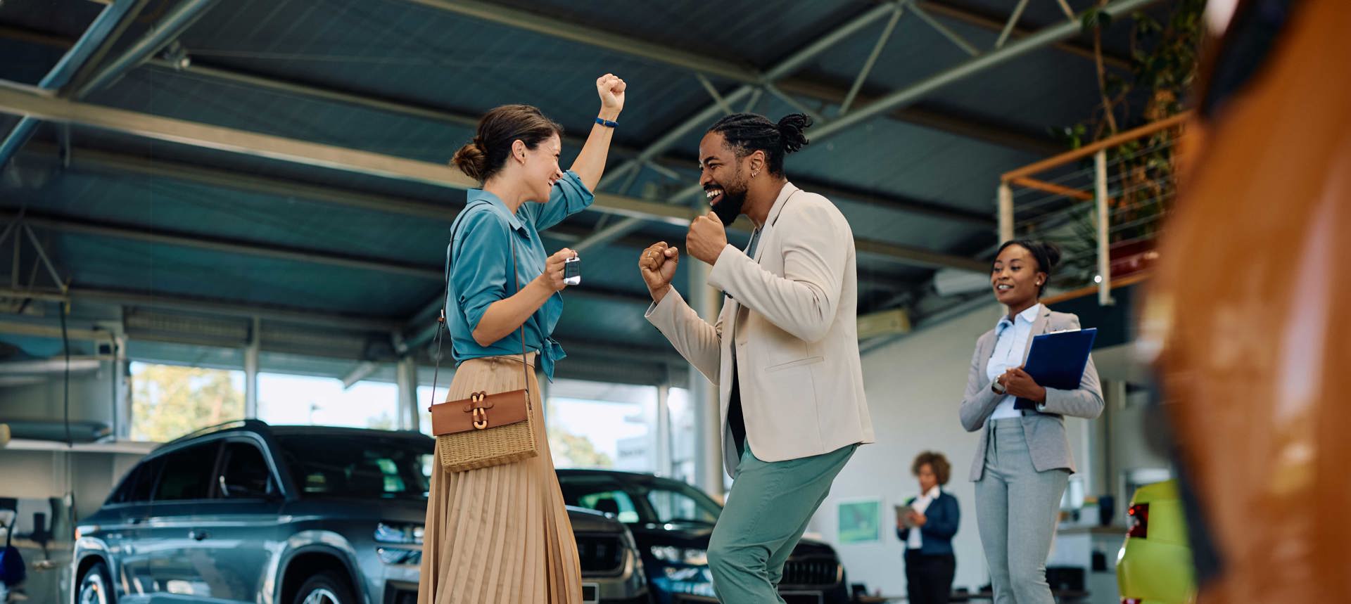 Two people dancing in a car dealership with the words 'more sales' in the background