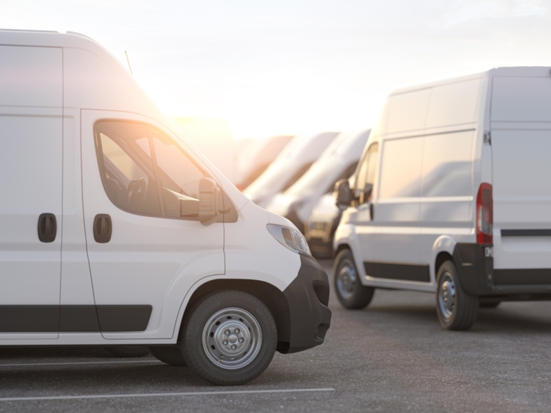 A large fleet of white vans parked on site.