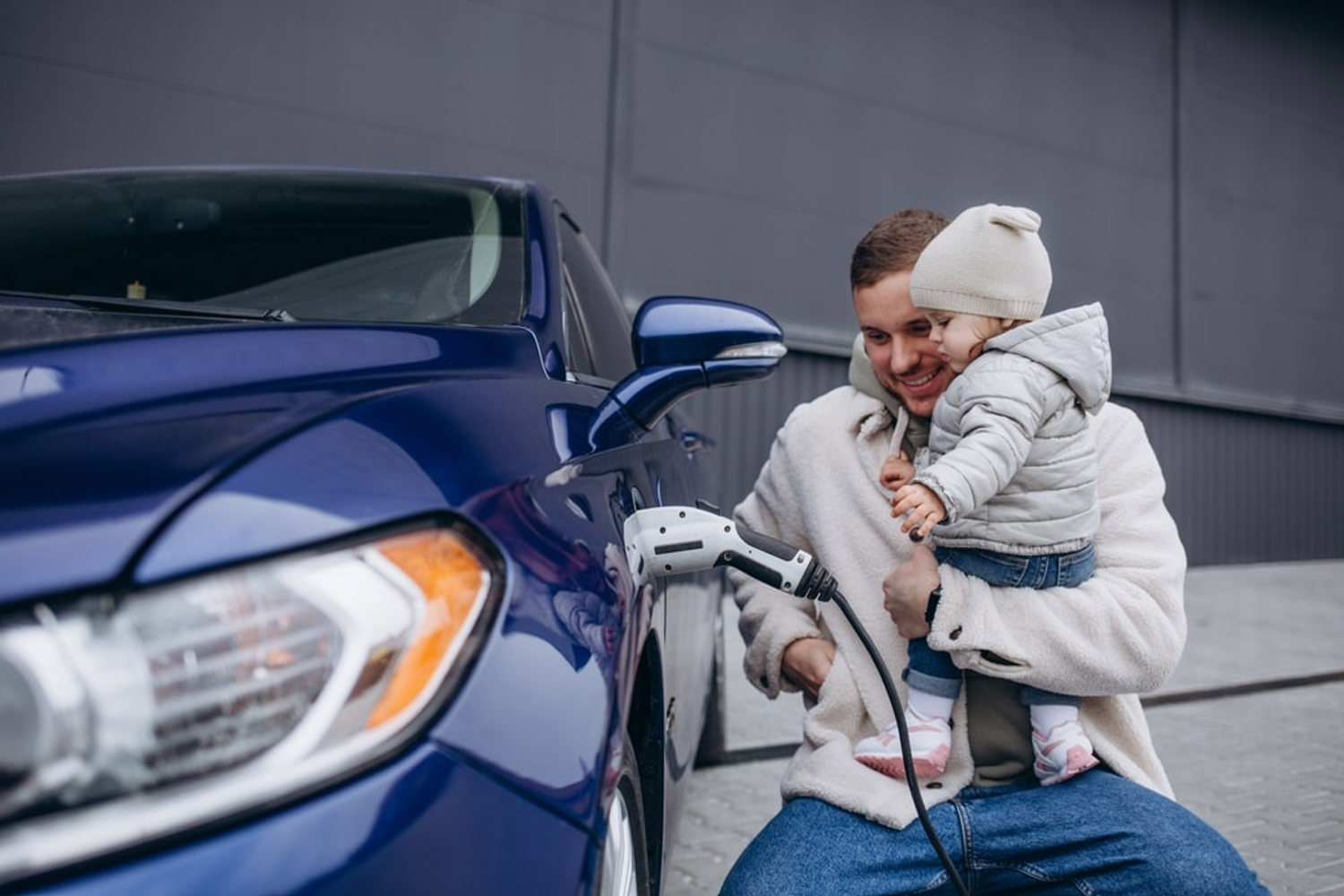 Man lifting his infant soon to charge their EV.